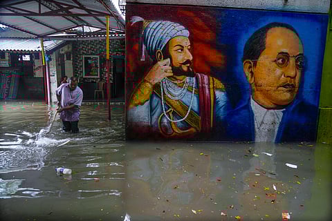 An employee tries to clear waterlogging at a school compound after heavy rainfall in Mumbai.