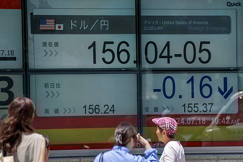 Pedestrians walk past an electronic board displaying the exchange rate for the Japanese yen against the US dollar in Tokyo on July 18, 2024.