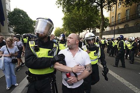 A man is detained as people attend the 'Enough is Enough' protest in Whitehall, London, Wednesday, July 31, 2024, following the fatal stabbing of three children at a Taylor-Swift themed holiday club on Monday in Southport.
