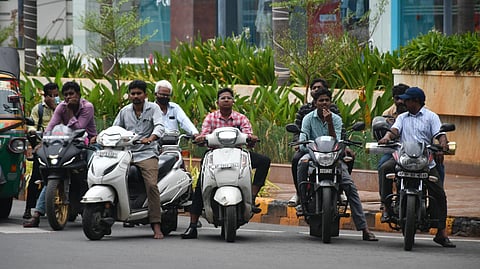Commuters ride their two wheelers without helmet in Vijayawada on Thursday.
