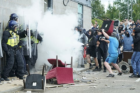 A protester uses a fire extinguisher on police officers as trouble flares during an anti-immigration protest outside the Holiday Inn Express in Rotherham, England, Sunday Aug. 4, 2024.
