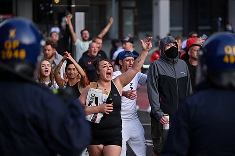 Police officers stand on duty as protesters shout slogans during the 'Enough is Enough' demonstration called by far-right activists in Bristol