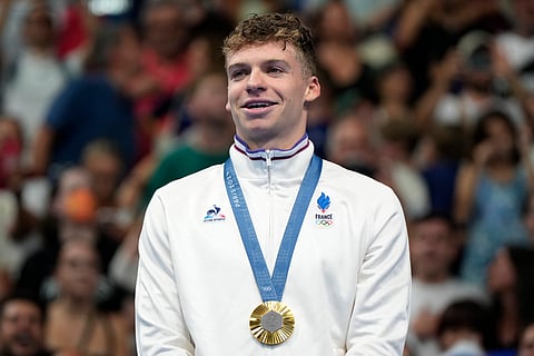 Gold medalist Leon Marchand stands on the winner's podium following the men's 200-meter breaststroke final at the Paris Olympics