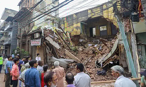 Local shop owners and residents near the debris of the house that collapsed due to heavy rains in Sabzi Mandi area in Delhi
