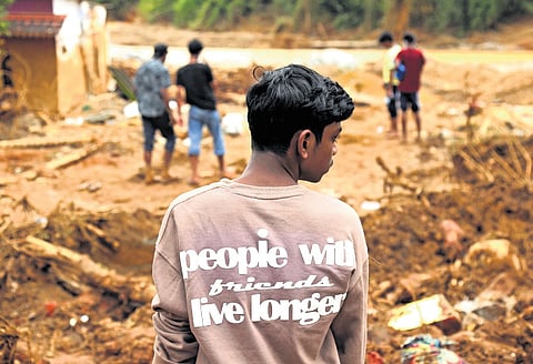 A boy, along with his friends, searches for valuables amid the debris of his collapsed house at landslide-hit Chooralmala in Wayanad on Sunday.