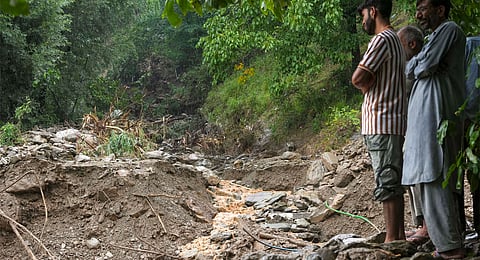 People stand near debris after a cloudburst, in Ganderbal district, Sunday, Aug. 4, 2024. A cloudburst in the district of Jammu and Kashmir has damaged a road, leading to the closing of the arterial Srinagar-Leh national highway, officials said on Sunday