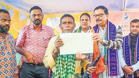 Pujari distributing land patta to an elderly at Kurla village