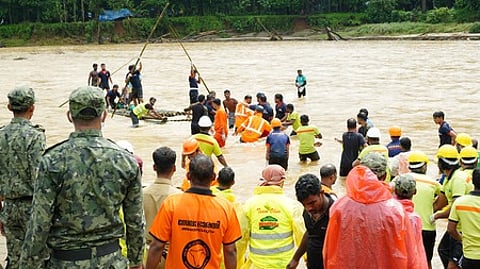 Rescue workers crossing the Chaliyar river on a makeshift raft with a remain of the landslide victim