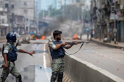 A policeman aims his weapon at protesters during a curfew imposed following violence during protests against Prime Minister Sheikh Hasina and her government, in Dhaka