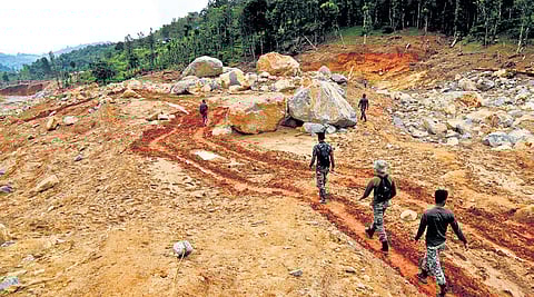Rescue workers passing through the landslide-hit area at Punchirimattam in Wayanad