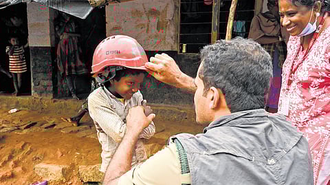Kalpetta forest range officer K Ashif shares a light moment with a child at a temporary relief camp set up for tribal community members at Attamala in Wayanad on Wednesday. The forest officials visit the camp daily with supplies as the tribal residents had expressed reluctance to shift to the relief camps at Meppadi