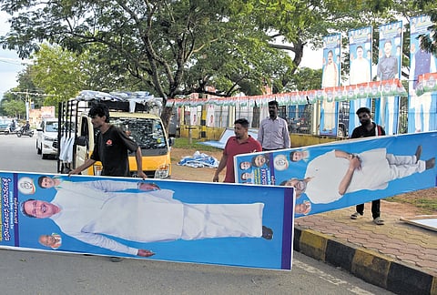 Workers erect Congress flex boards near Maharaja’s College Grounds in Mysuru on Thursday