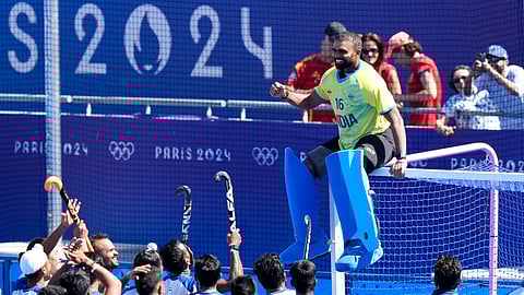 India's goalkeeper PR Sreejesh, in yellow jersey, sits on the goal cross-bars as India's players celebrate after winning the men's bronze medal field hockey match against Spain at the Yves-du-Manoir Stadium during the 2024 Summer Olympics.