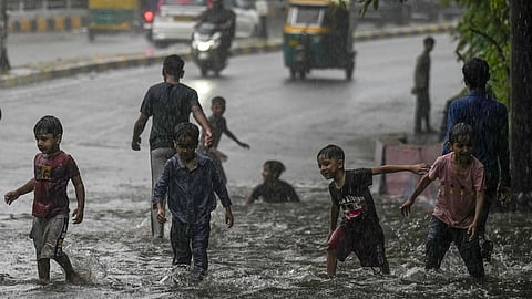 Children play on a waterlogged road in New Delhi.