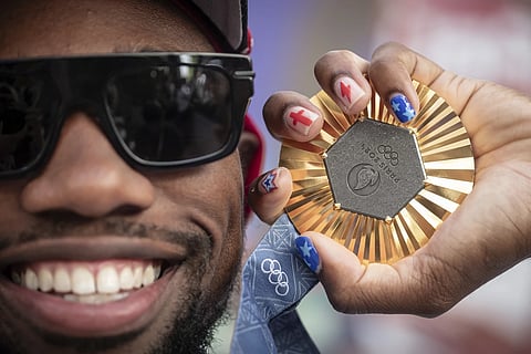 American Olympic champion Noah Lyles poses with his gold medal before an interview in Paris, France, Sunday, Aug 11, 2024.