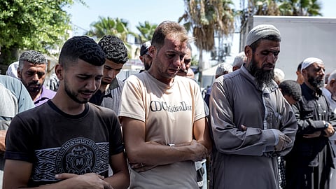 Mohammad Abu Al-Qumsan, Center, prays next to the bodies of his 4-day-old twin children, killed in the Israeli bombardment of the Gaza Strip, at a hospital in Deir al-Balah, Tuesday, Aug. 13, 2024.