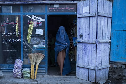 An Afghan woman exits a convenience shop in Kabul, Afghanistan on Dec 5, 2021.