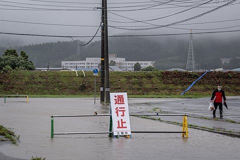 A man walks past a flooded road in the wake of "Typhoon No. 5", now classified as Severe Tropical Storm Maria, in Kuji city of Iwate prefecture on August 12, 2024.