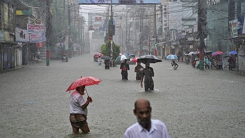 People navigate a flooded street following incessant rains in Tripura.