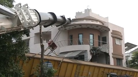 A crane used in the construction of the Metro rail project is seen resting on the bungalow it damaged in Surat on Thursday, Aug 22, 2024.