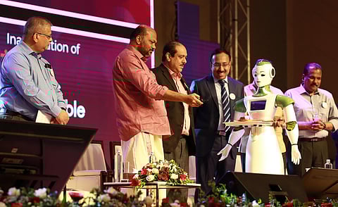 Industries Minister P Rajeeve receives a welcome gift from humanoid Saya ahead of his inaugurating the Robotics round table in Kochi