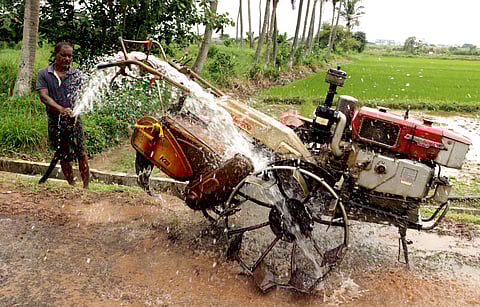 A farmer cleaning his ploughing machine with water at his farm on the outskirts of Bhubaneswar on Tuesday