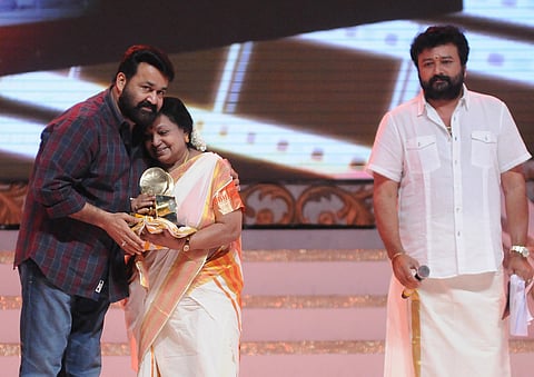 Actor Mohanlal presenting an award to TR Omana. Actor Jayaram is also seen.