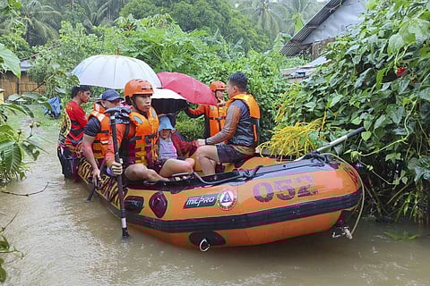 In this photo provided by the Philippine Coast Guard, rescuers use a rubber boat as they evacuate residents to higher grounds following floods due to a tropical storm in Allen, Northern Samar province, Philippines Sunday.
