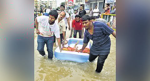 Volunteers helping an elderly woman by carrying her in a tub to shift her to a safe place