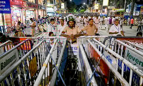 Police personnel stand guard near the barricades set up on a road leading to Lalbazar police headquarters in view of the protest march by junior doctors on Monday