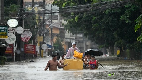 A resident rides an old refrigerator to avoid a flooded street caused by heavy rains from Tropical Storm Yagi, locally called Enteng, on Monday.