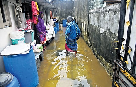 An elderly woman wades through floodwaters in Adarsh Nagar