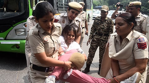 Police personnel detaining a teacher protesting near the Mandi House area on Thursday.