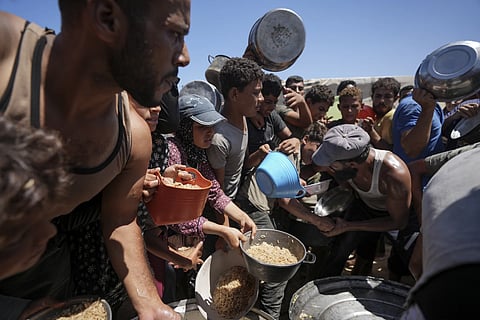 Displaced Palestinians gather for food distribution in Deir al Balah, Central Gaza Strip, Aug 23, 2024.