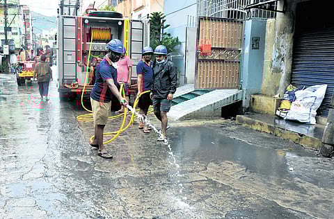 Fire department personnel cleaning the road as flood water recedes at One Town in Vijayawada on Sunday.