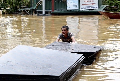 A man pushes a stack of plyboards in flood following typhoon Yagi in Hanoi, Vietnam on Tuesday, Sept 10, 2024.