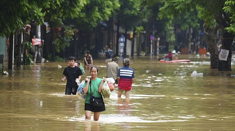 A woman carrying food wades in a flooded street in the aftermath of Cyclone Yagi.