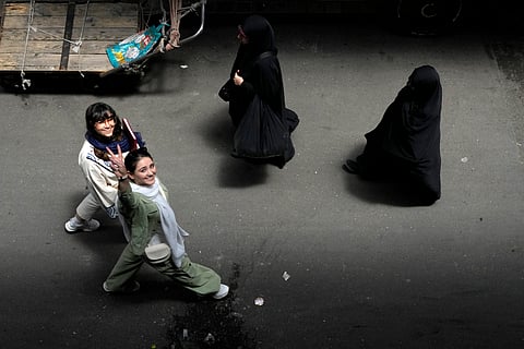 An Iranian woman without wearing her mandatory Islamic headscarf flashes a victory sign as two head-to-toe veiled women walk at the old main bazaar of Tehran, Iran, June 13, 2024.