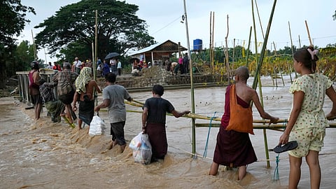 Local residents wade through flooded water at a broken bridge, in Naypyitaw, Myanmar.