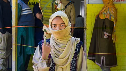 A woman shows her finger marked with indelible ink after casting her vote at a polling booth during the first phase of Jammu and Kashmir Assembly elections, in Shopian district
