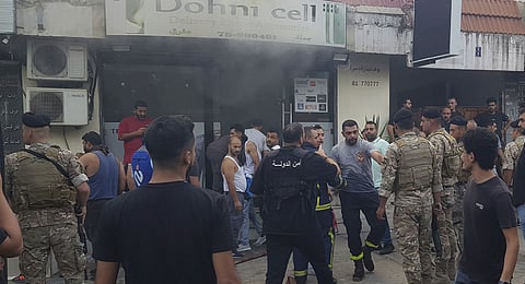 Lebanese soldiers and firefighters gather outside a mobile shop after what is believed to be the result of a walkie-talkie exploding inside it, in the southern port city of Sidon, Lebanon, Wednesday, Sept. 18, 2024.