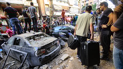 People gather in front of a building targeted by an Israeli strike in Beirut's southern suburbs on September 20, 2024