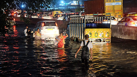 People walk through a flooded expressway service road after heavy rain in Gurugram, September 13, 2024.
