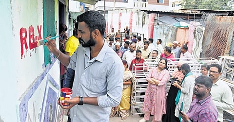 An official marks “RB-X” on a house, as part of the survey of structures along Musi riverbed at Chaderghat in Hyderabad on Thursday