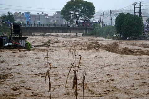 People watch the turbulent waters of Bagmati River from a bridge as the river flooded due to heavy rains in Kathmandu, Nepal, Saturday, Sept. 28, 2024.