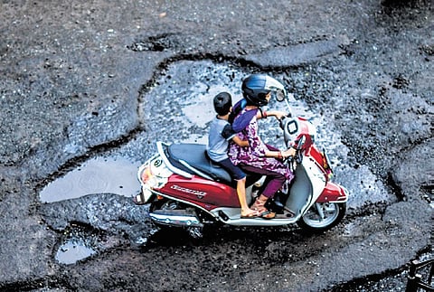 A woman and her kid struggle through potholes on Janpath near Vani Vihar;