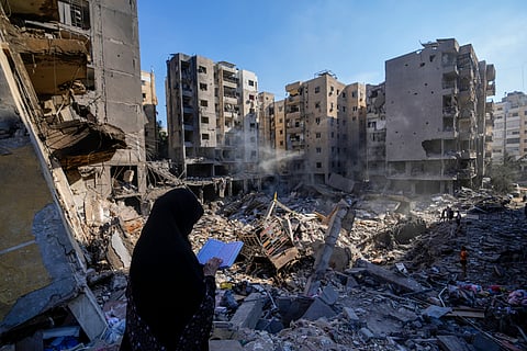 A woman reads the Quran at the site of the assassination of Hezbollah leader Hassan Nasrallah in Beirut's southern suburbs, Sunday, Sept. 29, 2024.