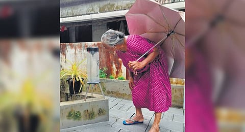 An elderly woman checks the rain gauge installed at her home.