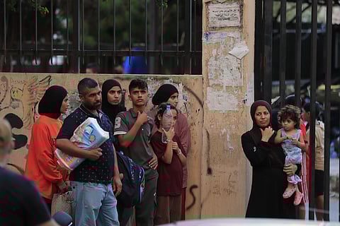 People fleeing the southern villages amid ongoing Israeli airstrikes, stand outside a school turned into a shelter in Sidon, Monday, Sept 23, 2024.