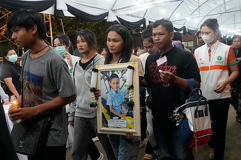 Victims' relatives carry portraits of the victims of a bus fire in a procession at Wat Khao Phraya Sangkharam School Lan Sak , Uthai Thani province, Thailand, Thursday, Oct. 3, 2024